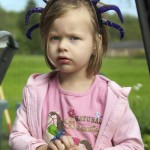 toddler in pink with spider headband, glaring at camera